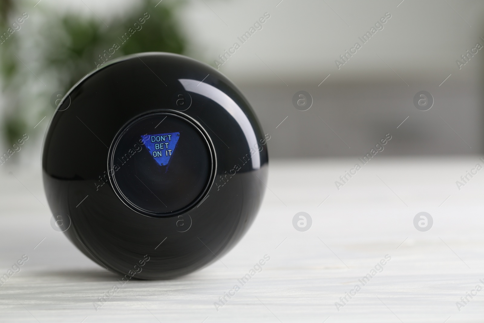 Photo of Magic eight ball with prediction Don't Bet On It on light table, closeup. Space for text