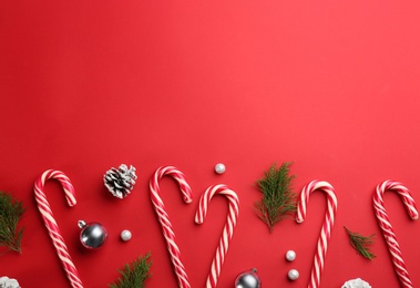 Flat lay composition with candy canes and Christmas decor on red background. Space for text