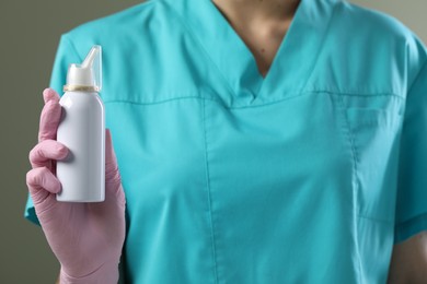 Woman holding nasal spray bottle on olive background, closeup. Space for text