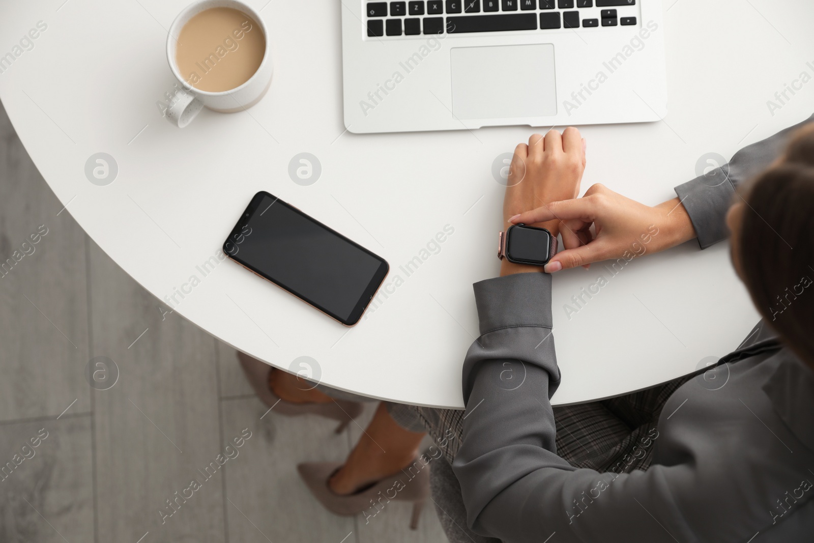 Image of Woman checking stylish smart watch at table indoors, top view