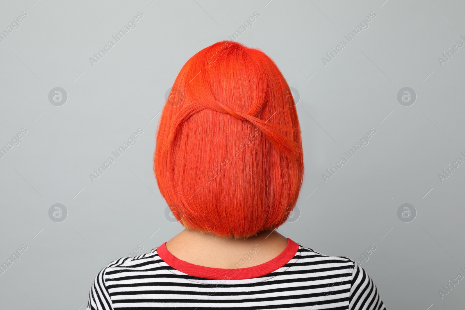 Photo of Young woman with bright dyed hair on grey background, back view