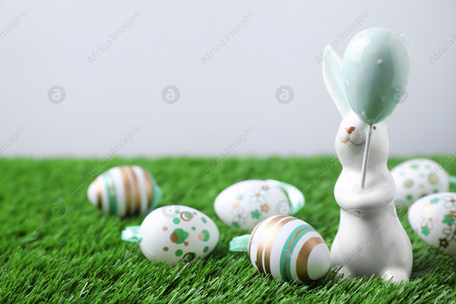 Photo of Easter bunny figure and eggs on green grass. Space for text