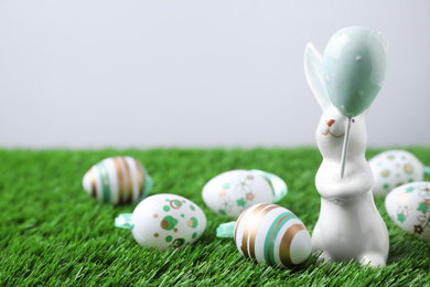 Photo of Easter bunny figure and eggs on green grass. Space for text