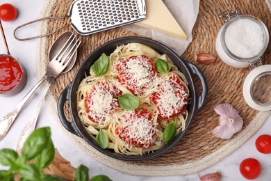 Photo of Delicious pasta with tomato sauce, basil and parmesan cheese on white marble table, flat lay