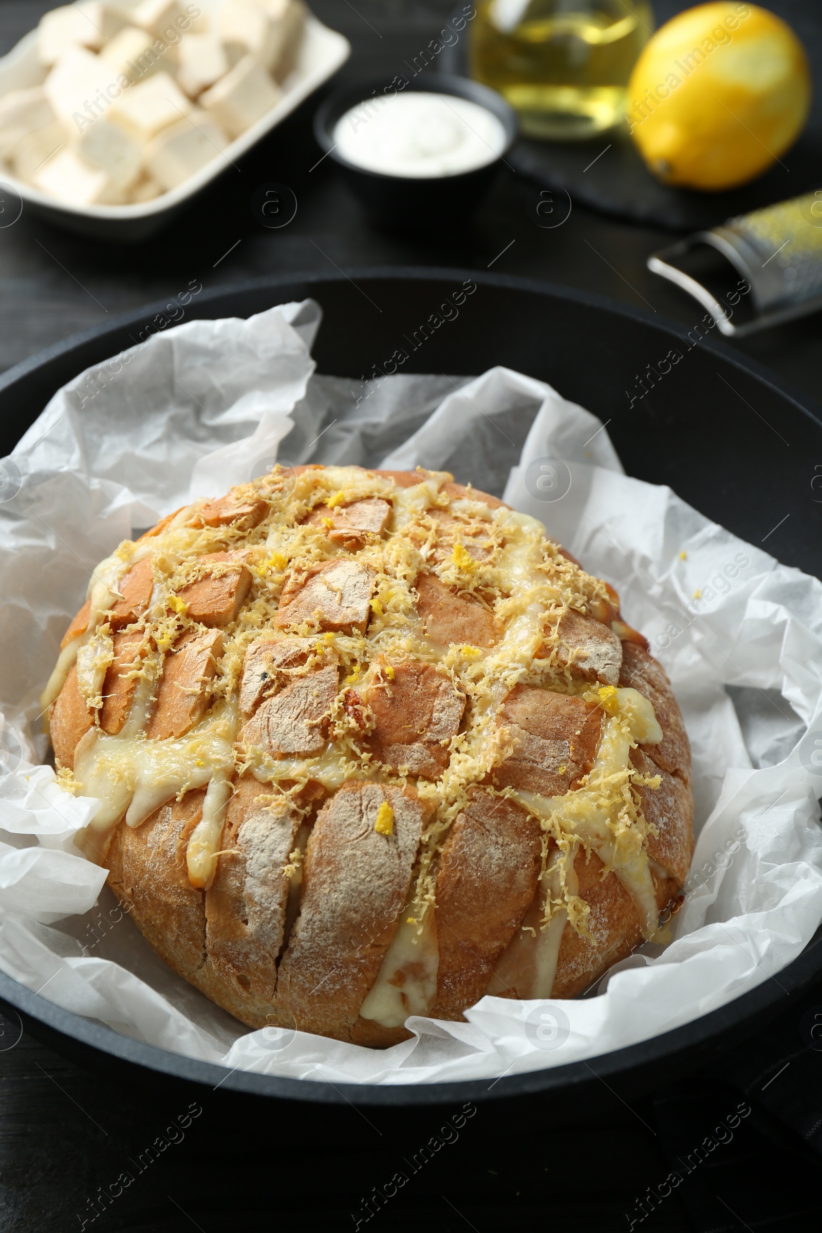 Photo of Freshly baked bread with tofu cheese and lemon zest on black table