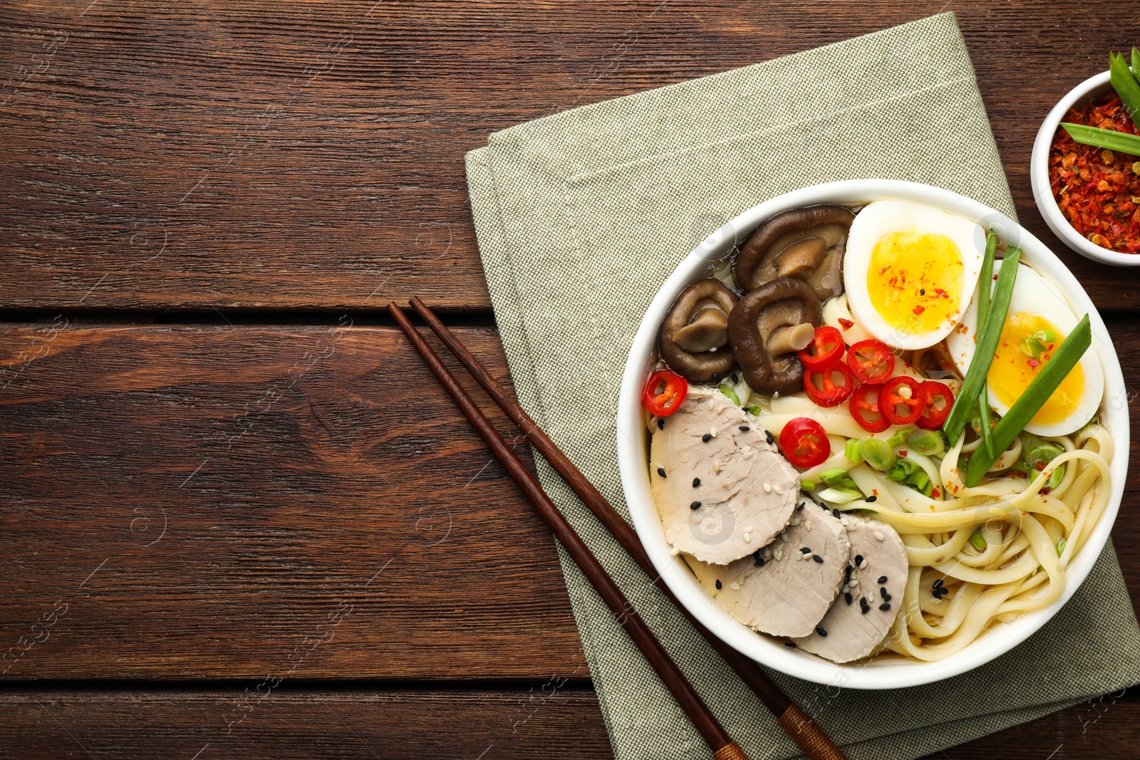 Photo of Delicious ramen with meat in bowl served on wooden table, flat lay. Space for text. Noodle soup