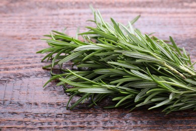 Photo of Fresh green rosemary twigs on wooden table, closeup
