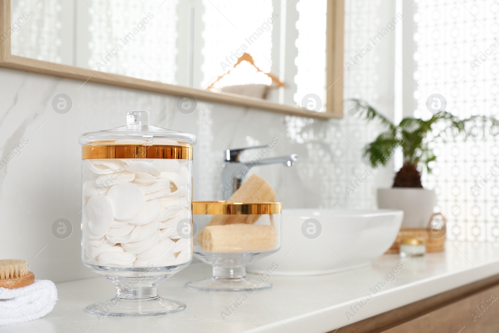 Photo of Jars with cotton pads and loofah sponges on bathroom countertop