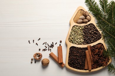 Different spices, nuts and fir branches on white wooden table, flat lay. Space for text