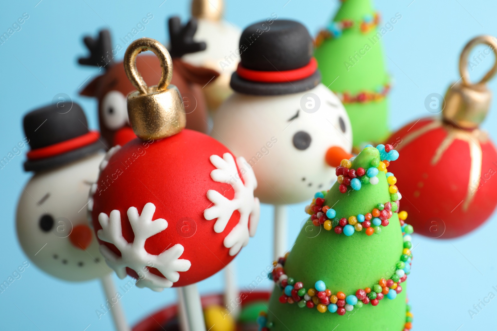 Photo of Delicious Christmas themed cake pops on light blue background, closeup