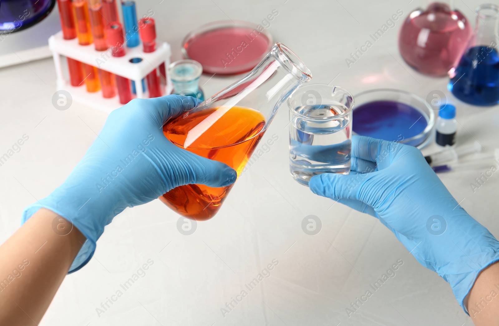 Photo of Scientist pouring reagent into beaker at table in chemistry laboratory, closeup