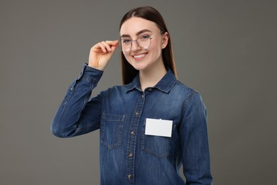 Photo of Happy woman with blank badge on grey background