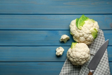 Photo of Fresh cauliflowers on light blue wooden table, top view. Space for text