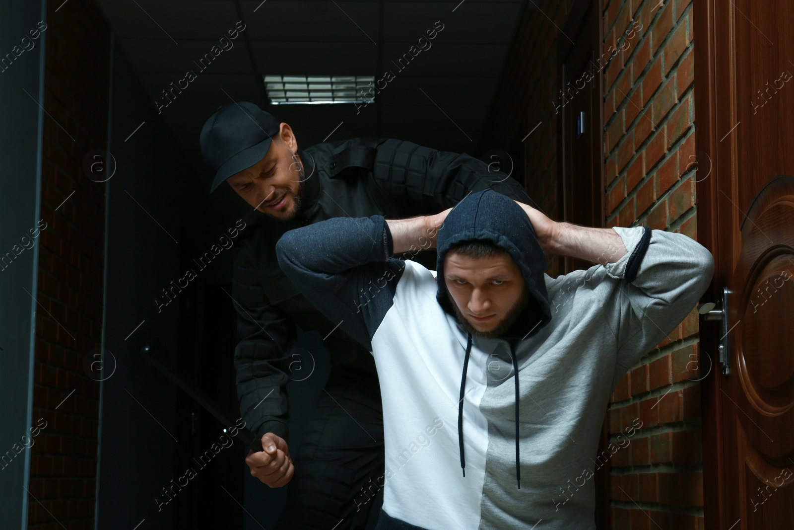 Photo of Officer with baton escorting criminal in police station