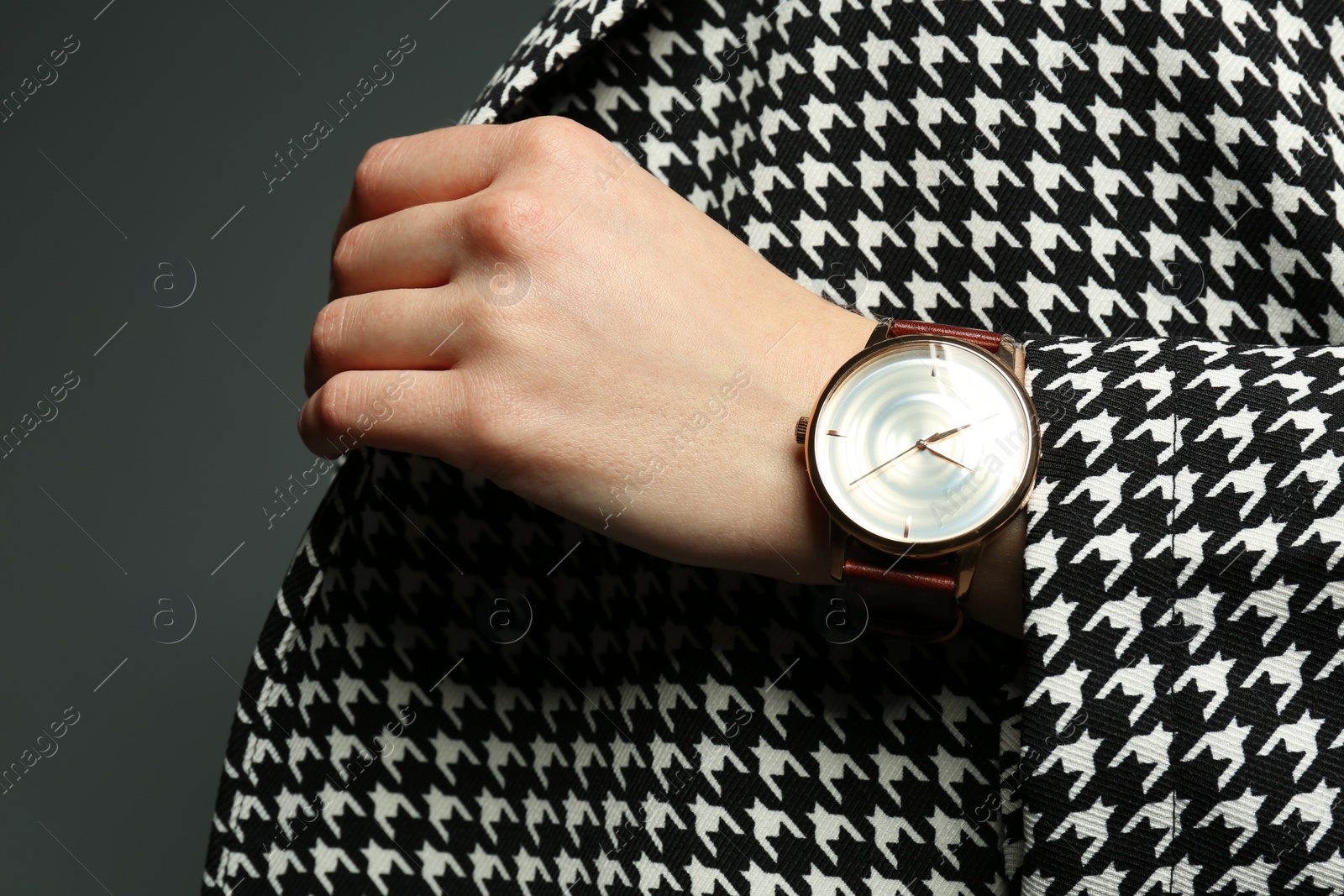Photo of Woman wearing luxury wristwatch on grey background, closeup