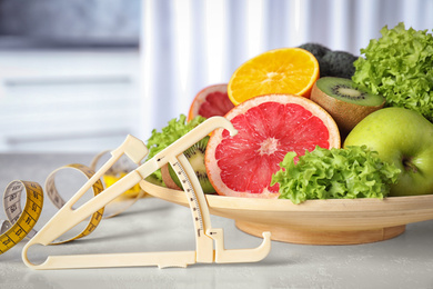 Photo of Body fat caliper, measuring tape, vegetables and fruits on table. Diet plan from nutritionist
