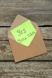 Photo of Envelope and phrase Yes You Can on wooden table, top view. Motivational quote