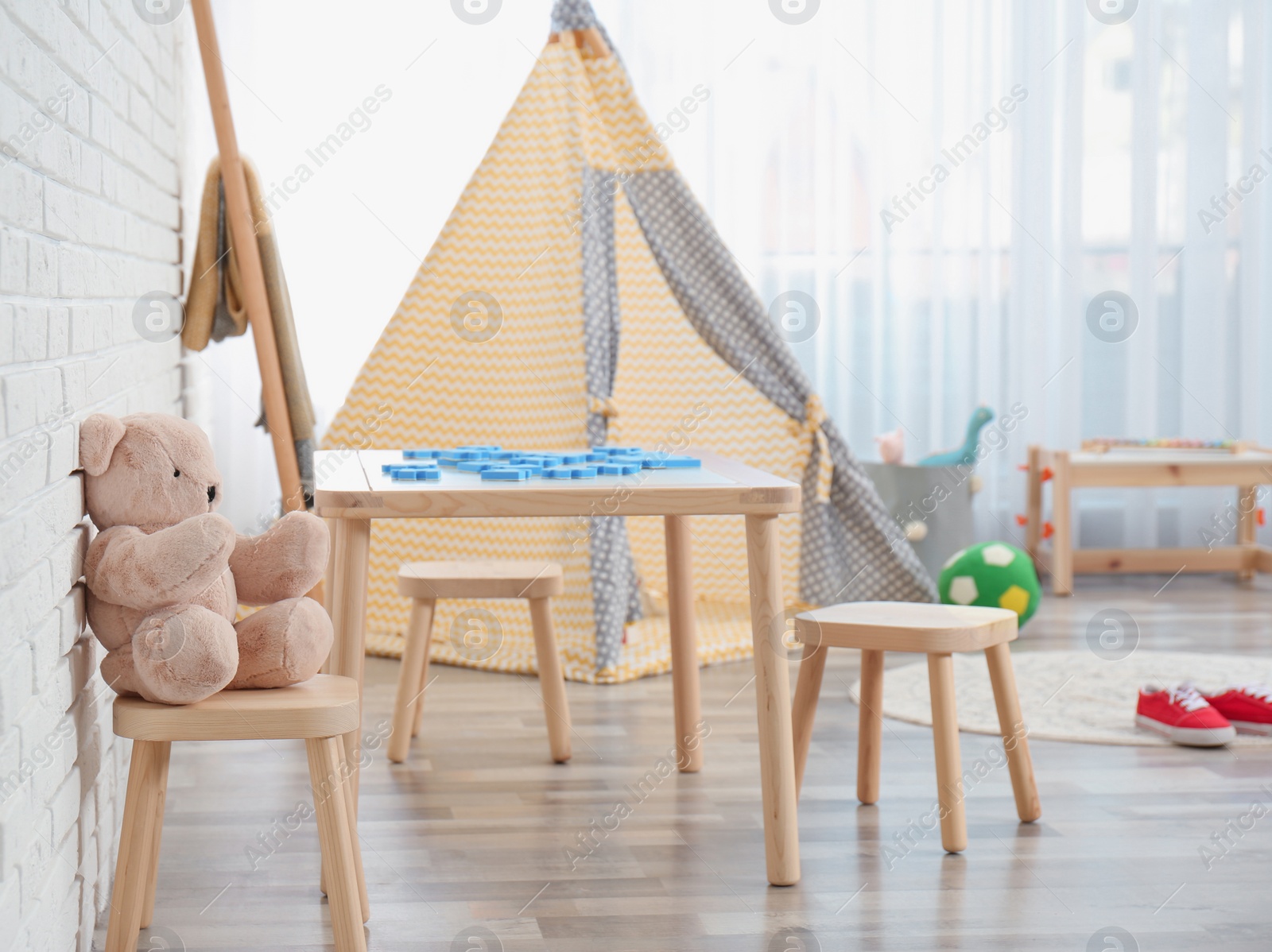 Photo of Cozy kids room interior with table, stools and play tent