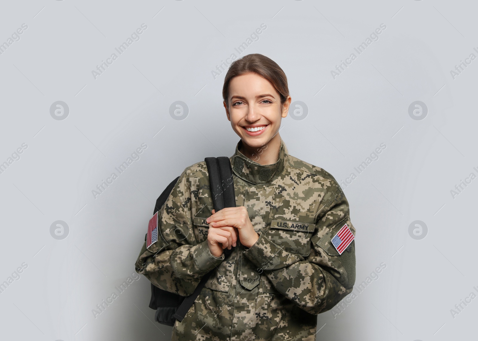 Photo of Female cadet with backpack on light grey background. Military education