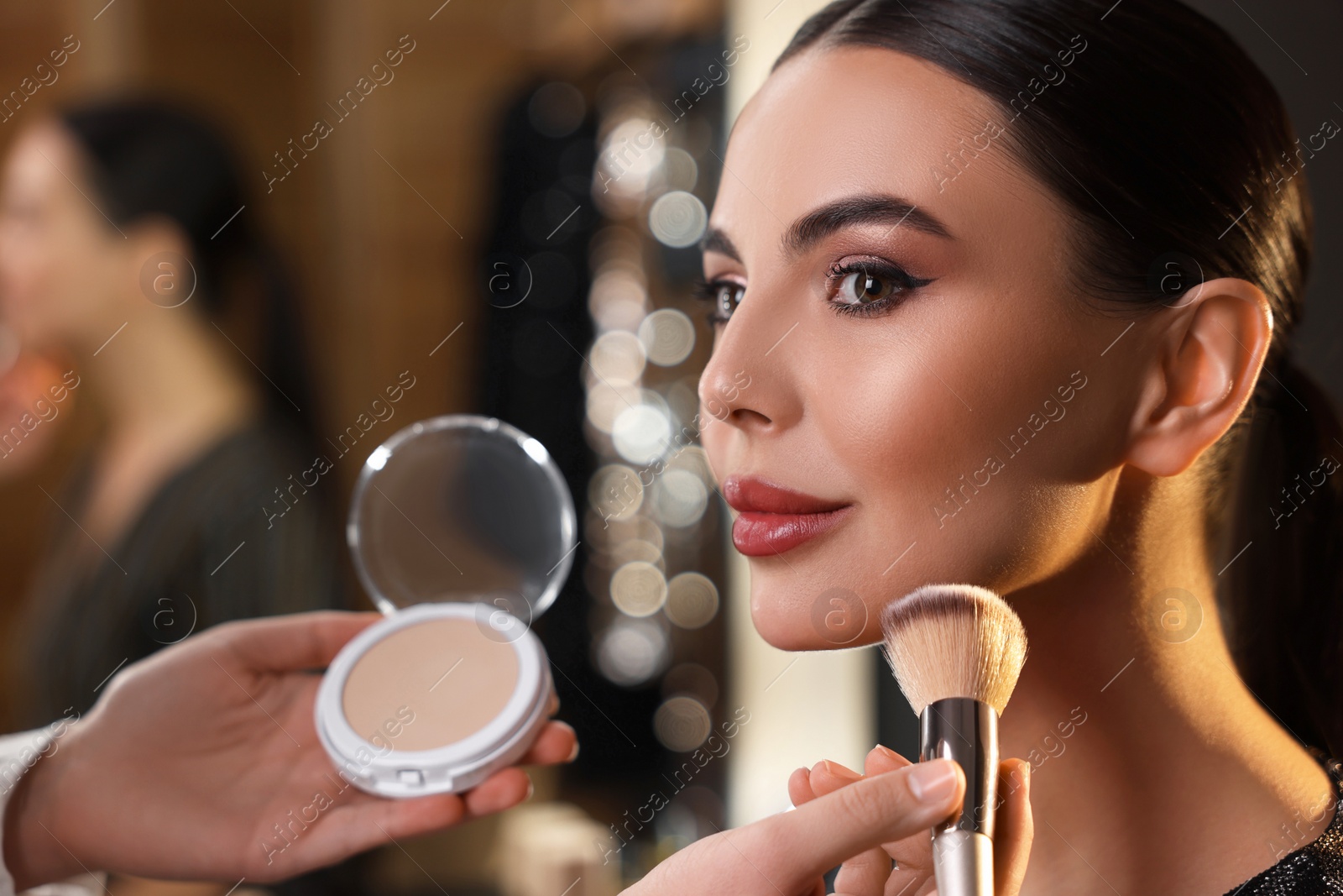 Photo of Makeup artist working with beautiful woman in dressing room, closeup