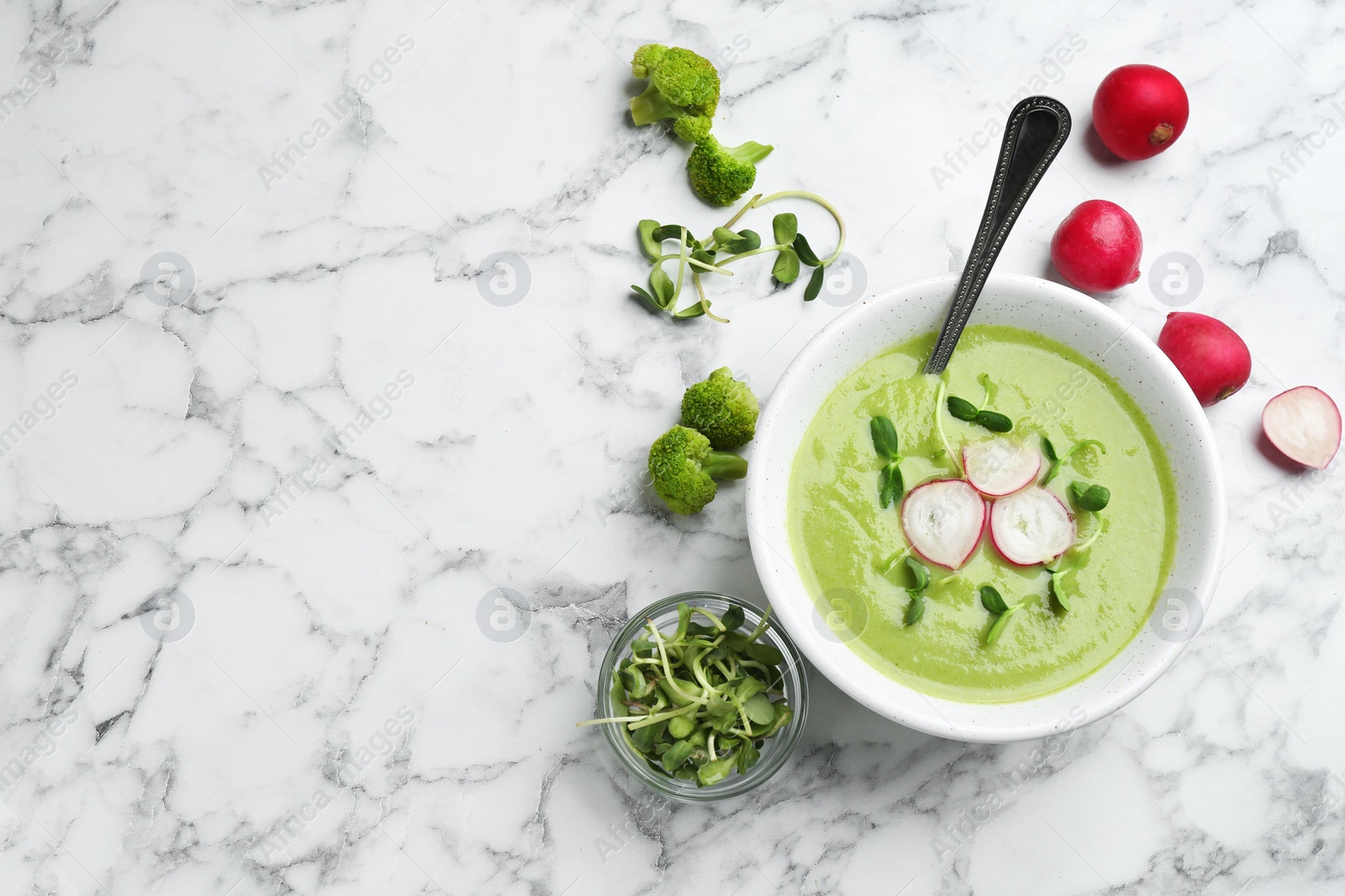 Photo of Flat lay composition with bowl of broccoli cream soup on white marble table, space for text