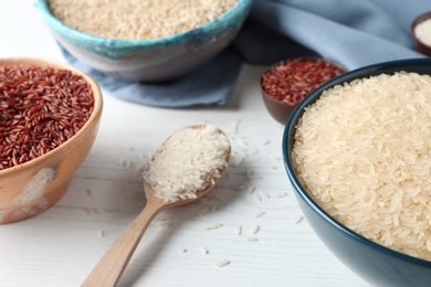 Photo of Composition with brown and other types of rice on white wooden background