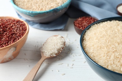 Composition with brown and other types of rice on white wooden background