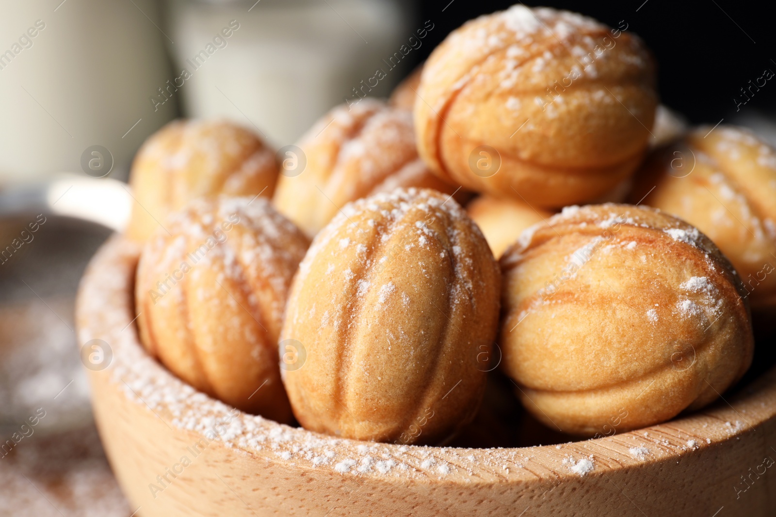 Photo of Delicious nut shaped cookies with powdered sugar in wooden bowl, closeup