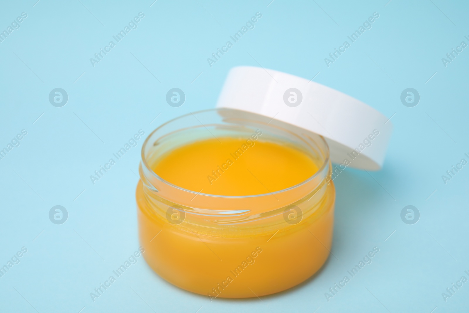 Photo of Open jar of petrolatum on light blue background, closeup