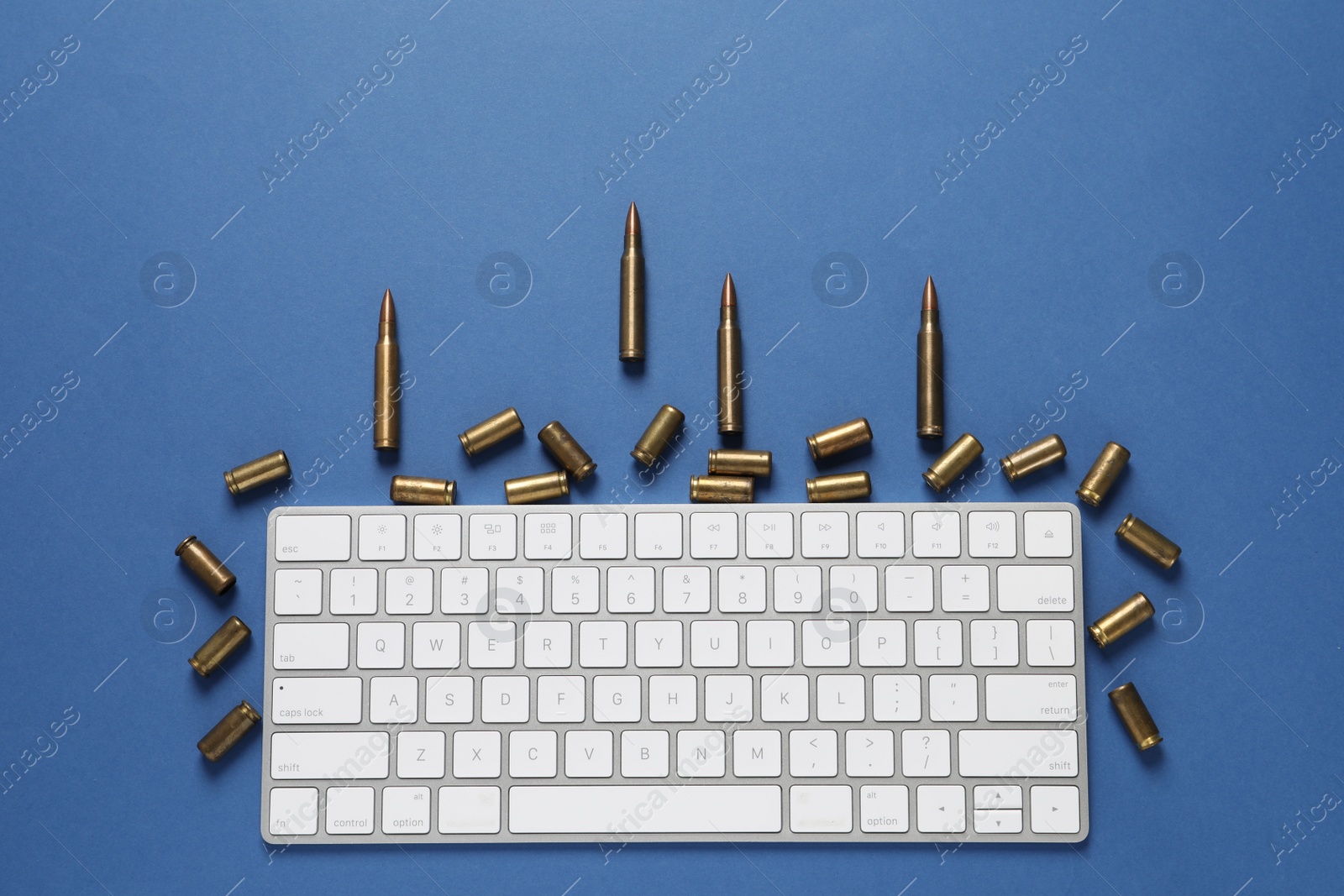 Photo of Bullets and computer keyboard on blue background, flat lay. Hybrid warfare concept