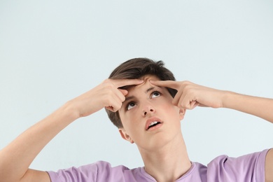 Photo of Teenage boy with acne problem on light background