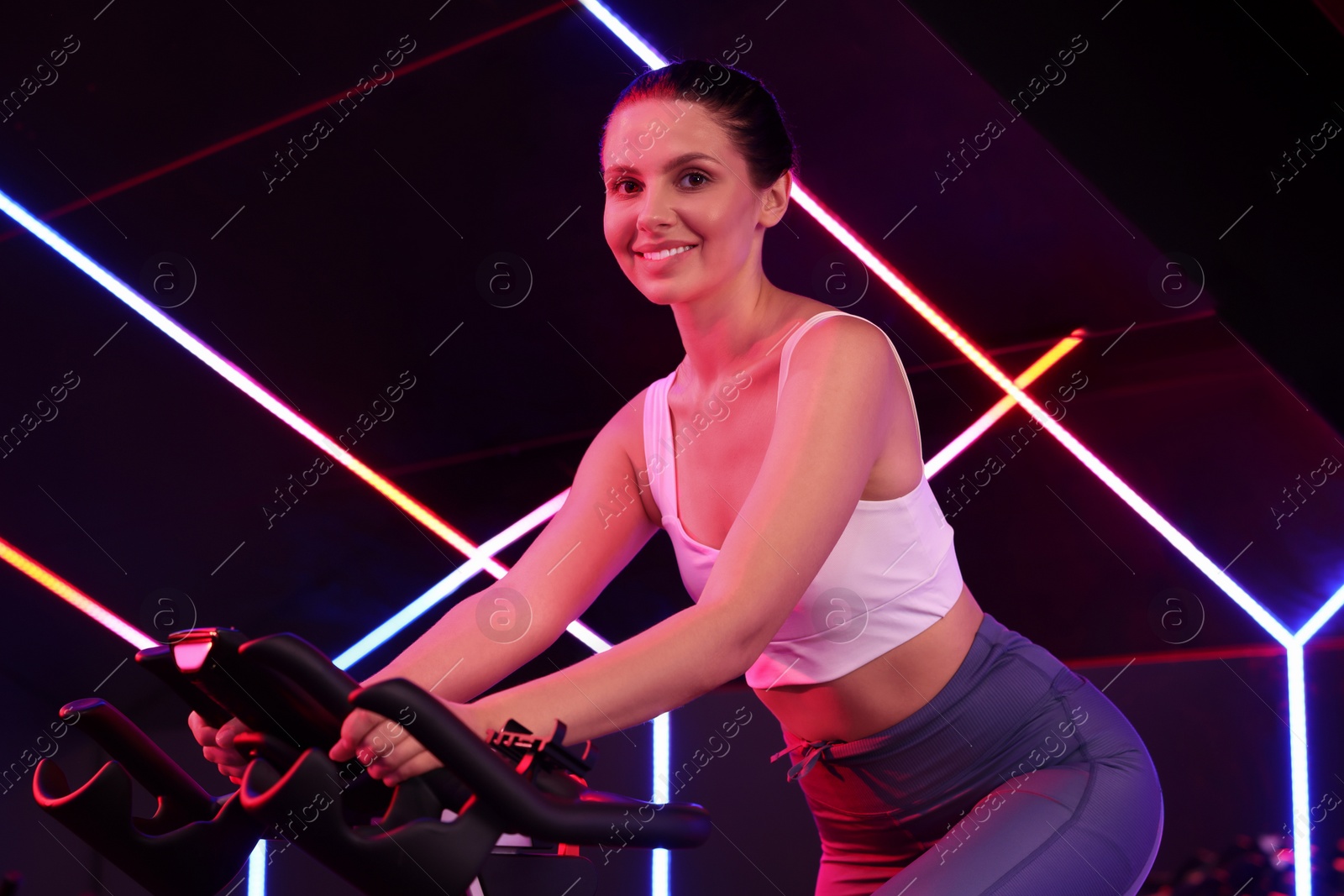 Photo of Young woman training on exercise bike in fitness club