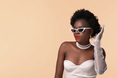 Photo of Fashionable portrait of beautiful woman with stylish sunglasses on beige background, space for text