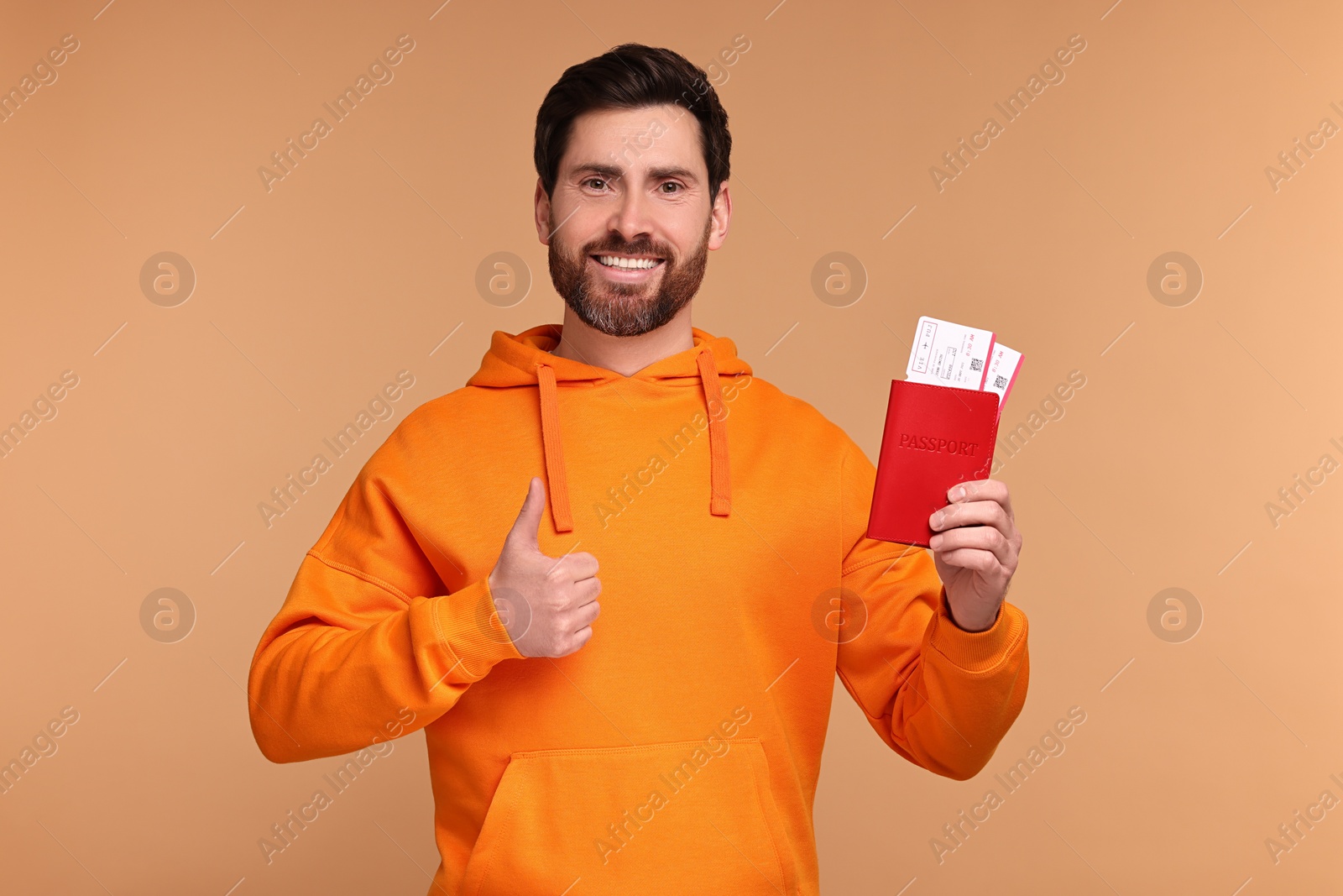 Photo of Smiling man with passport and tickets showing thumb up on beige background