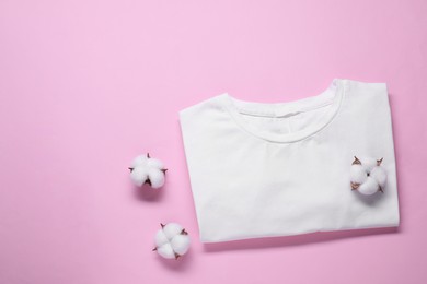 Photo of Fluffy cotton flowers and white t-shirt on pink background, flat lay. Space for text