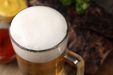 Photo of Glass mug with tasty beer on table, closeup. Space for text