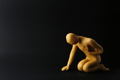 Photo of Plasticine figurehuman asking help on black background. Space for text