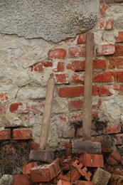 Sledgehammers on pile of bricks near wall outdoors