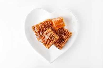 Heart shaped plate with honeycomb pieces isolated on white, top view