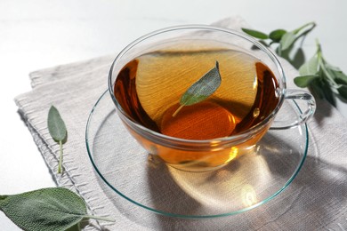 Photo of Cup of aromatic herbal tea with sage on white table