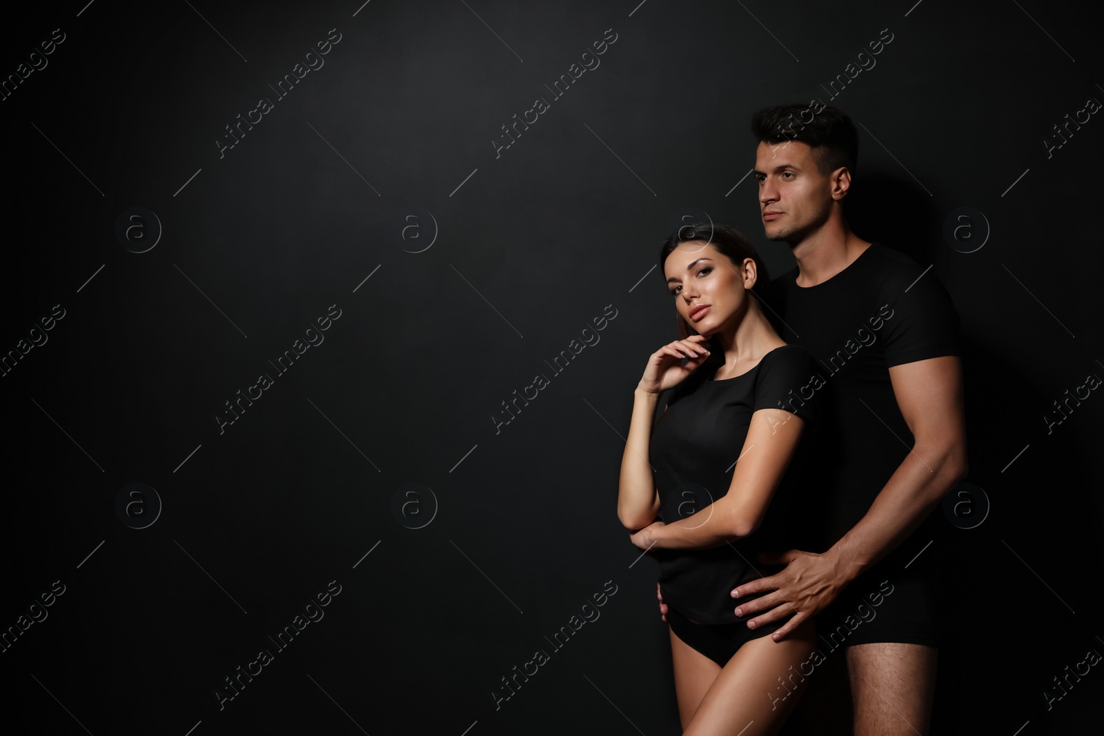 Image of Young couple wearing underwear on black background, space for text