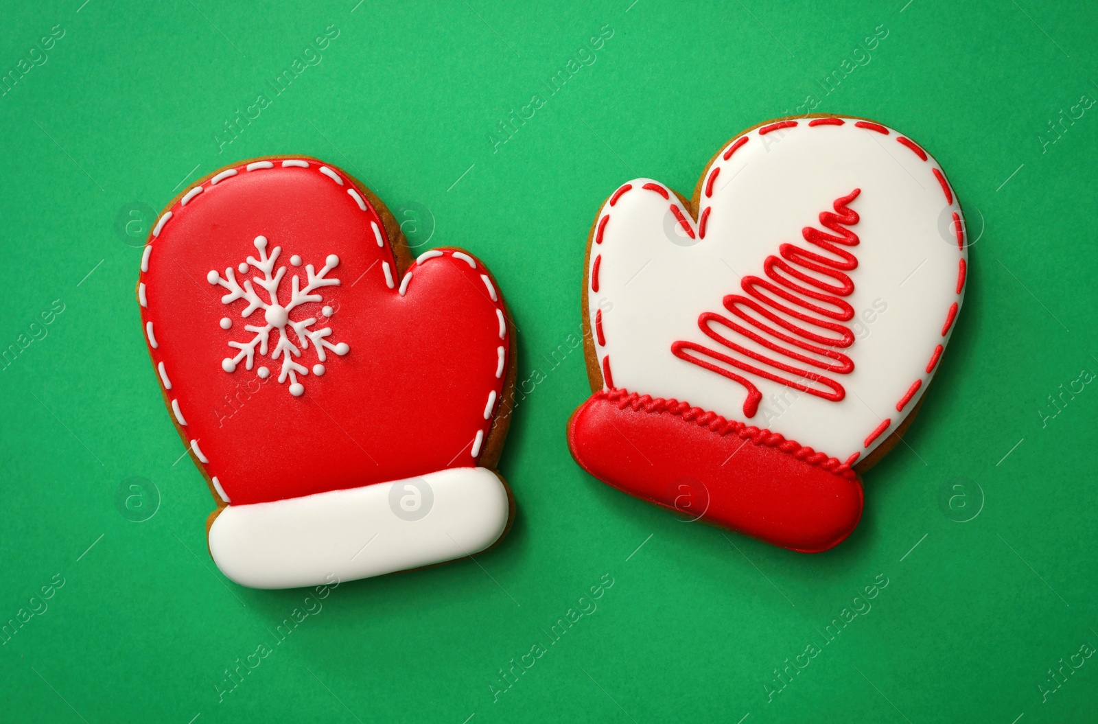 Photo of Christmas mitten shaped gingerbread cookies on green background, flat lay