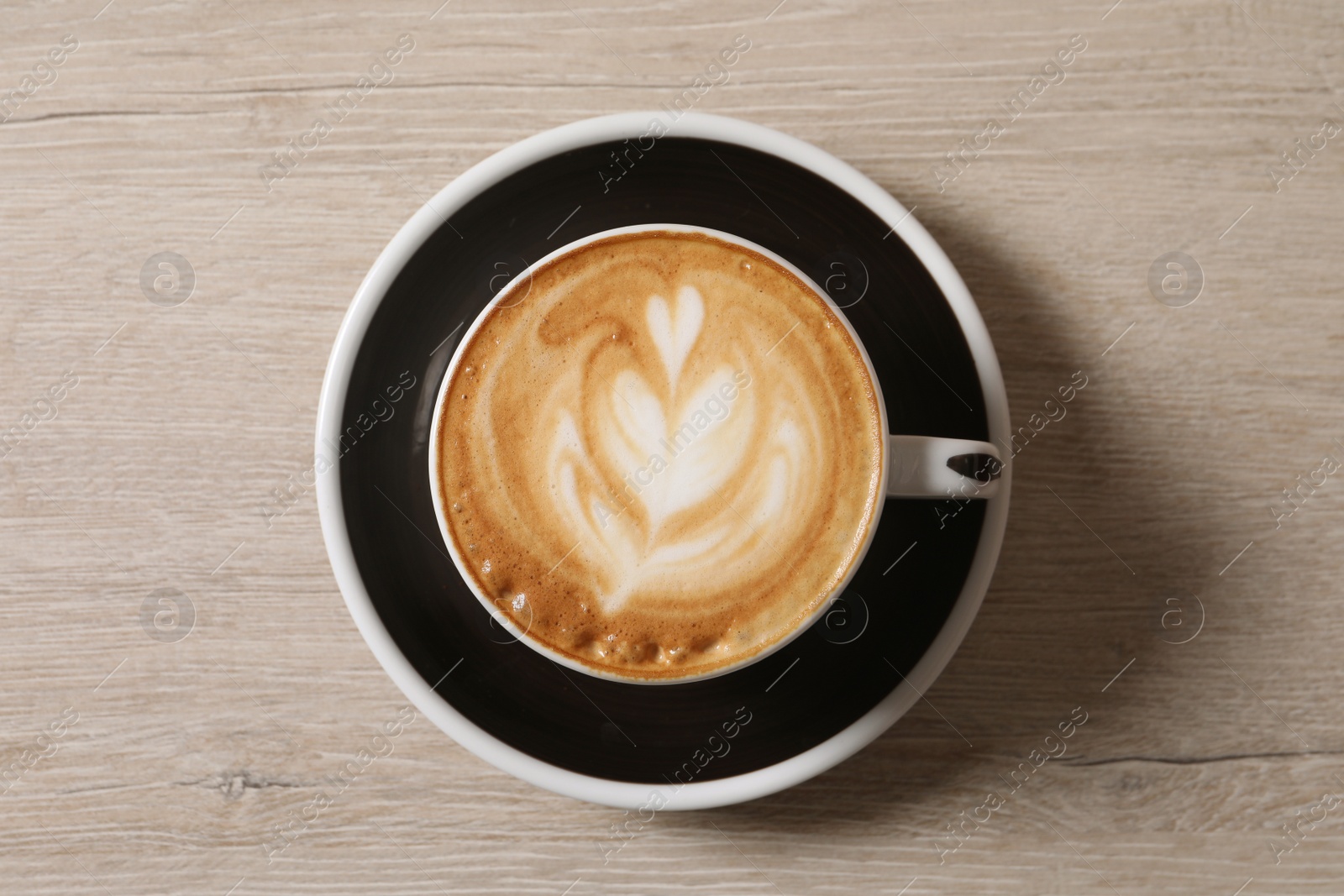 Photo of Cup of aromatic coffee on wooden table, top view