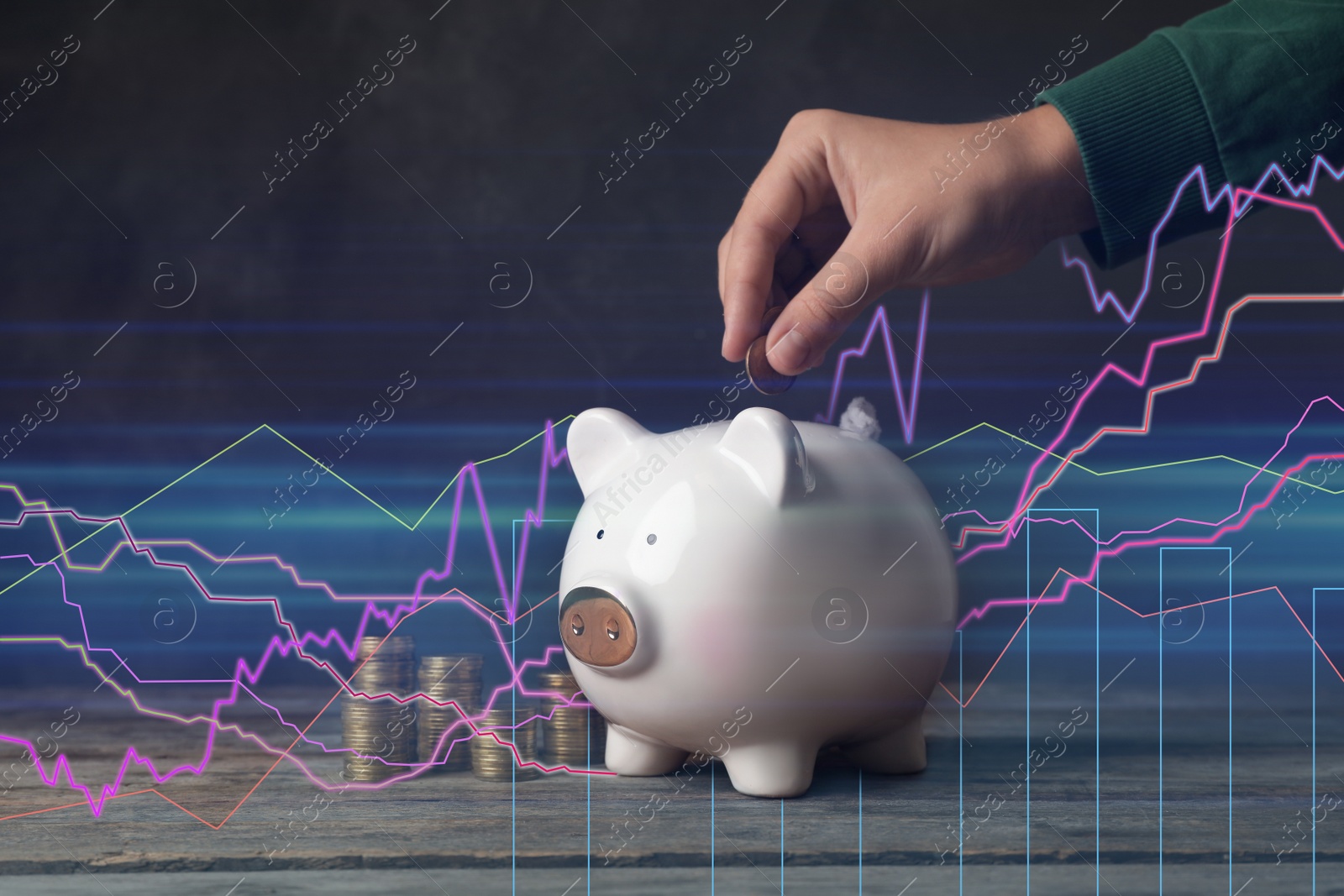 Image of Woman putting coin into piggy bank on wooden table. Illustration of financial graphs