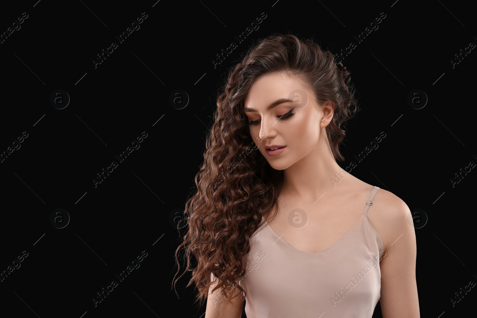 Photo of Beautiful young woman with long curly brown hair on black background, space for text