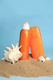 Photo of Sand with bottles of sunscreens and seashells against light blue background. Sun protection