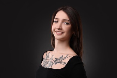 Portrait of smiling tattooed woman on black background