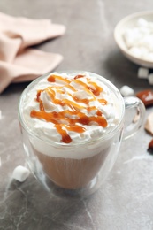 Cup of coffee with caramel topping on grey background