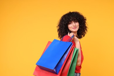 Photo of Happy young woman with shopping bags on yellow background