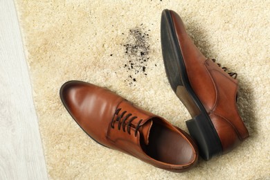 Photo of Brown shoes and mud on beige carpet, top view